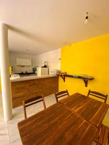 a kitchen with a wooden table and a yellow wall at Pousada Caminho de Moises in Maragogi