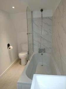 a white bathroom with a tub and a toilet at Barn in beautiful Countyside in Watford