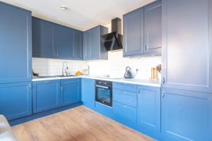 a blue kitchen with white appliances and blue cabinets at Modern and Beautiful 2 Bedroom Flat - Haggerston in London