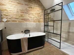 La salle de bains est pourvue d'une baignoire et d'une douche en verre. dans l'établissement Château du Mauny, gîtes et chambres d'hôtes en Bourgogne, à Rosey