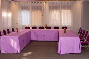 Das Berliner Hotel في كامبالا: غرفة مع طاولتين وكراسي مع مفارش طاولات أرجوانية