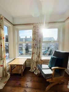 a living room with a chair and a table and windows at The Anchorage , Gorleston on Sea in Gorleston-on-Sea