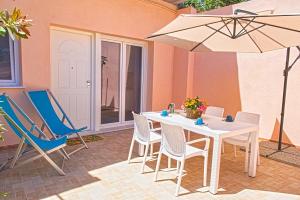 eine Terrasse mit Tisch, Stühlen und Sonnenschirm in der Unterkunft Appartamenti Mare Portoferraio in Portoferraio