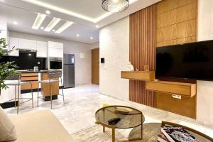 a living room with a large television and a kitchen at The Suite of Artists - Central - By AppartAli in Casablanca