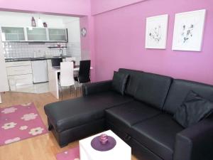 a living room with a black couch and a pink wall at Apartments Nela in Ohrid