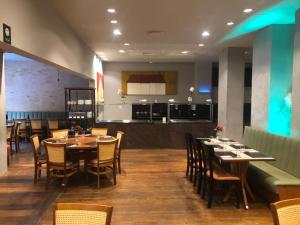comedor con mesas y sillas y cocina en San Diego Apart- Hotel en Belo Horizonte