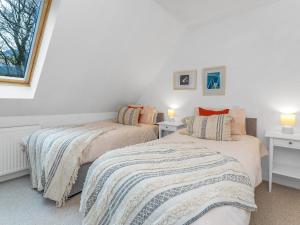 2 camas en una habitación con paredes blancas y ventana en Cheerful Stays: 4 Bedroom Cottage in Arrochar en Arrochar