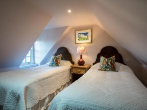 a attic bedroom with two beds and a lamp at Auchengool House in Kirkcudbright