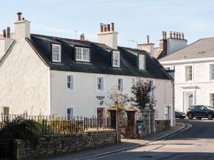 a white house with a black roof on a street at Auchengool House in Kirkcudbright