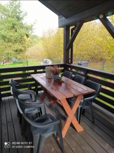 a wooden table and chairs on a deck at Całoroczny domek letniskowy nad zalewem Chańcza in Życiny