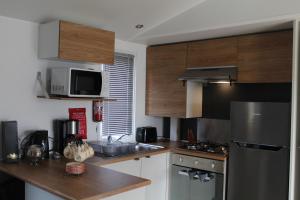 a kitchen with wooden cabinets and a stainless steel refrigerator at La nature en famille in Litteau