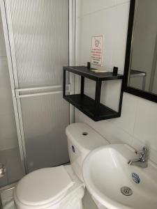 a bathroom with a toilet and a sink and a mirror at Hotel Bisou in Cali