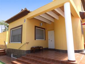una casa con paredes amarillas y porche en Playa Eucaliptos 1A, en Isla Cristina