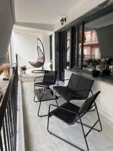 d'un balcon avec 4 chaises noires et des fenêtres. dans l'établissement M&F Meteora Apartments #1, à Kalambaka