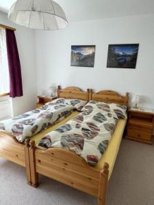 ein Schlafzimmer mit einem Holzbett mit einer Bettdecke in der Unterkunft Chesa Islas, Wohnng 11 in Pontresina