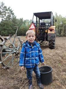 a young boy standing in front of a tractor at Domek nad stawem 