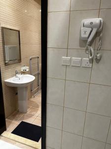 a bathroom with a sink and a phone on the wall at الرياض بارك للاجنحة الفندقية in Riyadh