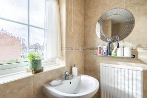 a bathroom with a sink and a mirror and a window at Ori's Hut in Luton