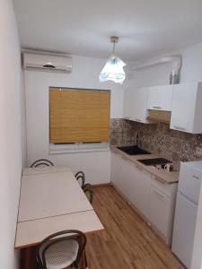uma cozinha com armários brancos e uma mesa e cadeiras em Apartmany Makarská em Drvenik
