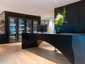 a bar with a black counter with a vase of flowers at Das Flint in Dornbirn