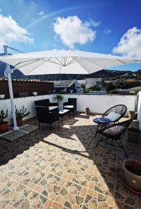 a patio with chairs and a large white umbrella at Appartamento Central in Lipari
