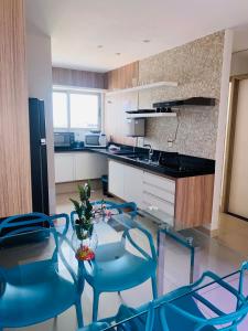 cocina con mesa de cristal y sillas azules en Apartamento Duplex Vista Mar em Natal, en Natal