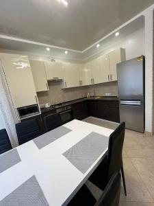 eine Küche mit einem weißen Tisch und einem Kühlschrank in der Unterkunft Maxim in Winnyzja