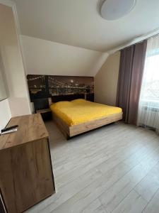 um quarto com uma cama amarela e uma janela em Maxim em Vinnytsya