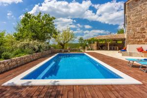 a swimming pool on a wooden deck with a house at Villa Bell Aria in Grižane
