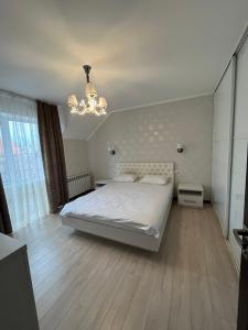 a bedroom with a white bed and a chandelier at Maxim in Vinnytsya