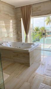 a large bath tub in a room with a large window at Relais de Charme Boutique Hotel Pititinga in Rio do Fogo