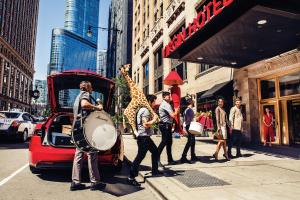 a group of people playing drums on a city street at Virgin Hotels Chicago in Chicago