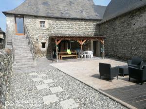 a stone building with a patio with chairs and a table at Peyo et Foodie in Escou