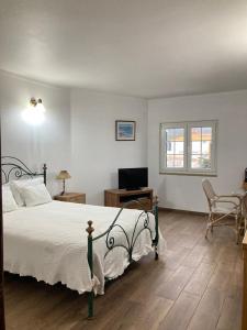 a bedroom with a bed and a desk and a television at Casa da Nazaré in Portinho da Arrábida