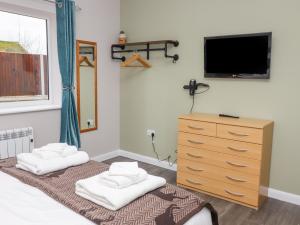 a bedroom with a dresser and a tv on the wall at The Old Stables in Oasby