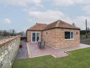 a brick house with a patio and a wall at The Old Stables in Oasby