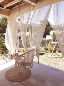 eine schwingende Hängematte auf einer Veranda mit Aussicht in der Unterkunft Maison ensoleillée de plain-pied ouvert sur un jardin clôturé in Mallemoisson