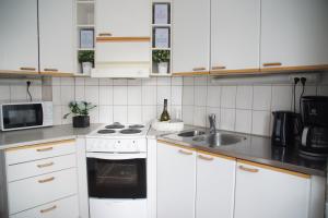 cocina con armarios blancos, fogones y fregadero en 3-room apartment in Oulu center, parking en Oulu