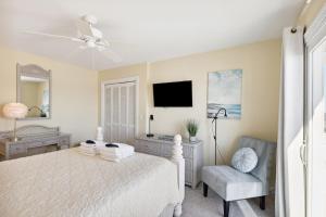 a bedroom with a bed and a chair and a television at 1015 E Arctic Ave Dolphins Folly Oceanfront Home in Folly Beach