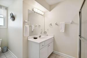 a white bathroom with a sink and a mirror at 1015 E Arctic Ave Dolphins Folly Oceanfront Home in Folly Beach