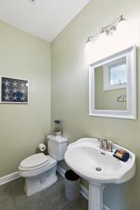 a bathroom with a sink and a toilet and a mirror at 1015 E Arctic Ave Dolphins Folly Oceanfront Home in Folly Beach