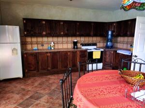 a kitchen with wooden cabinets and a white refrigerator at Amankaya Atitlan in Cerro de Oro