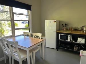 uma cozinha com uma mesa e um frigorífico branco em Bush Retreat Farm Stay 1BR em Alberton West