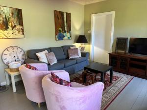 uma sala de estar com um sofá azul e cadeiras cor-de-rosa em Bush Retreat Farm Stay 1BR em Alberton West
