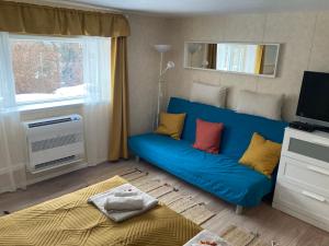 a living room with a blue couch and a bed at Lilakő Apartman in Mátraszentimre