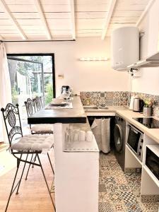 een keuken met een aanrecht en stoelen. bij CASA AZUL - jardin, calme, tennis in Nîmes