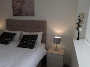a bedroom with a bed and a lamp on a night stand at KCS Broad Street Apartment Birmingham in Birmingham