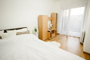 a white bedroom with a large bed and a window at Apartman Dalija in Valjevo