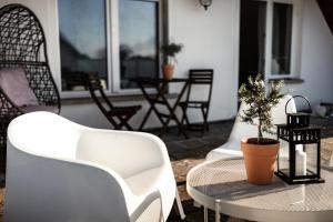 un patio con sillas blancas y una mesa con una maceta en Schwarze Möwe, en Grambin