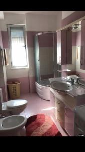 ein Badezimmer mit zwei Waschbecken, einem WC und einer Badewanne in der Unterkunft Holiday Apartment in Lezha
